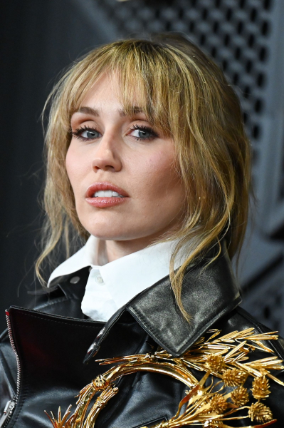 Miley Cyrus posing in an ornately goldaccessorized black leather jacket